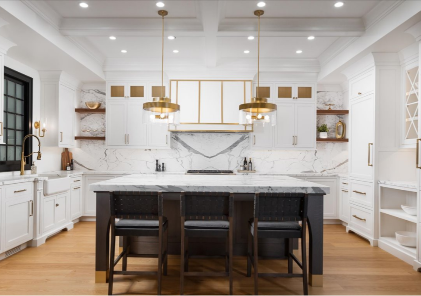 White kitchen with marble island and brass pendants